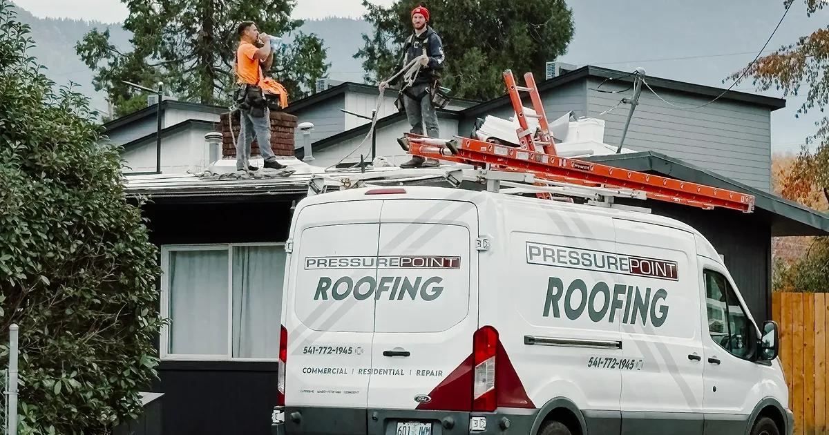 A branded Pressure Point Roofing van at a job site