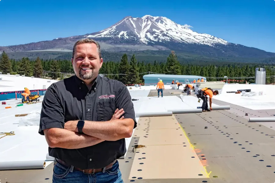 A Pressure Point Roofing team member on a commercial roof with the Cascade mountains behind